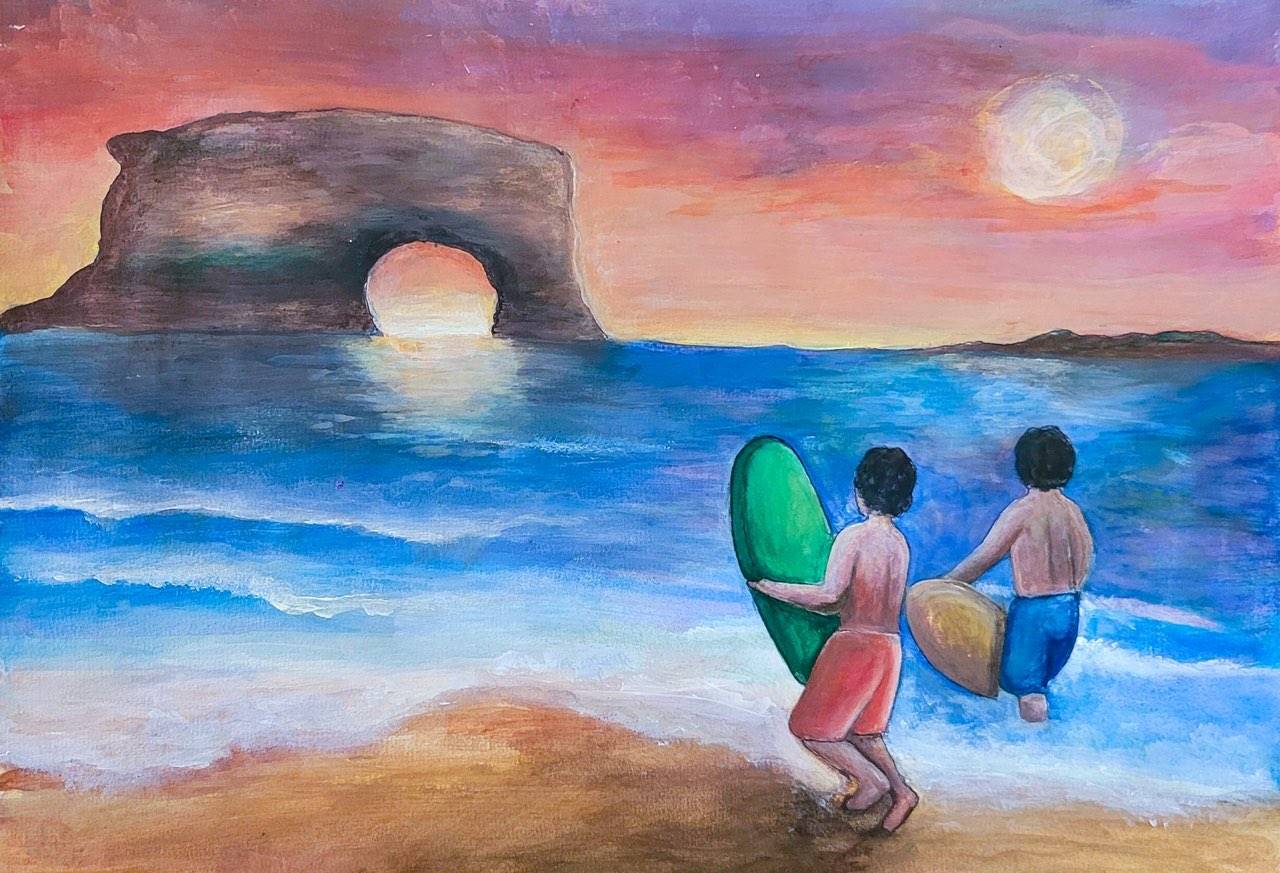 Two youth with surf boards stand in the waves in front of Natural Bridges.