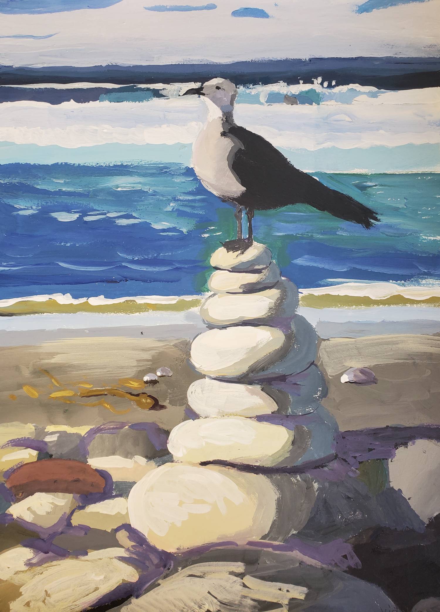 A gull perches on top of a stack of stones on the beach