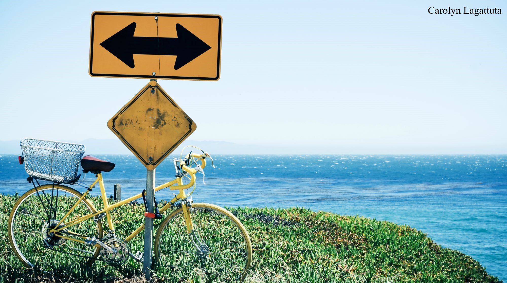A photo of a bicycle parked against a traffic sign on a bluff above the ocean, by Carolyn Lagattuta