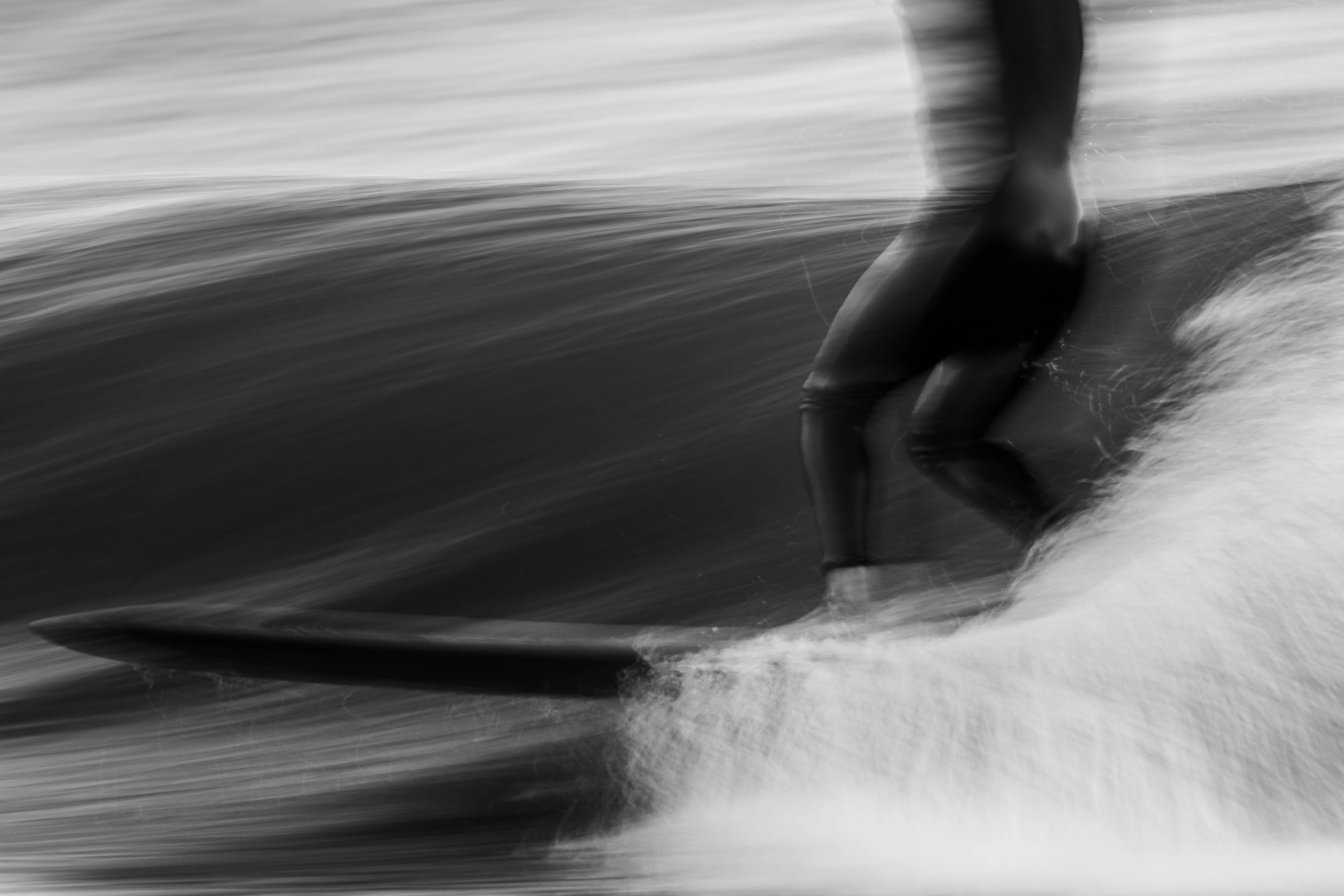 a blurry view of the legs of a surfboarder as they glide by