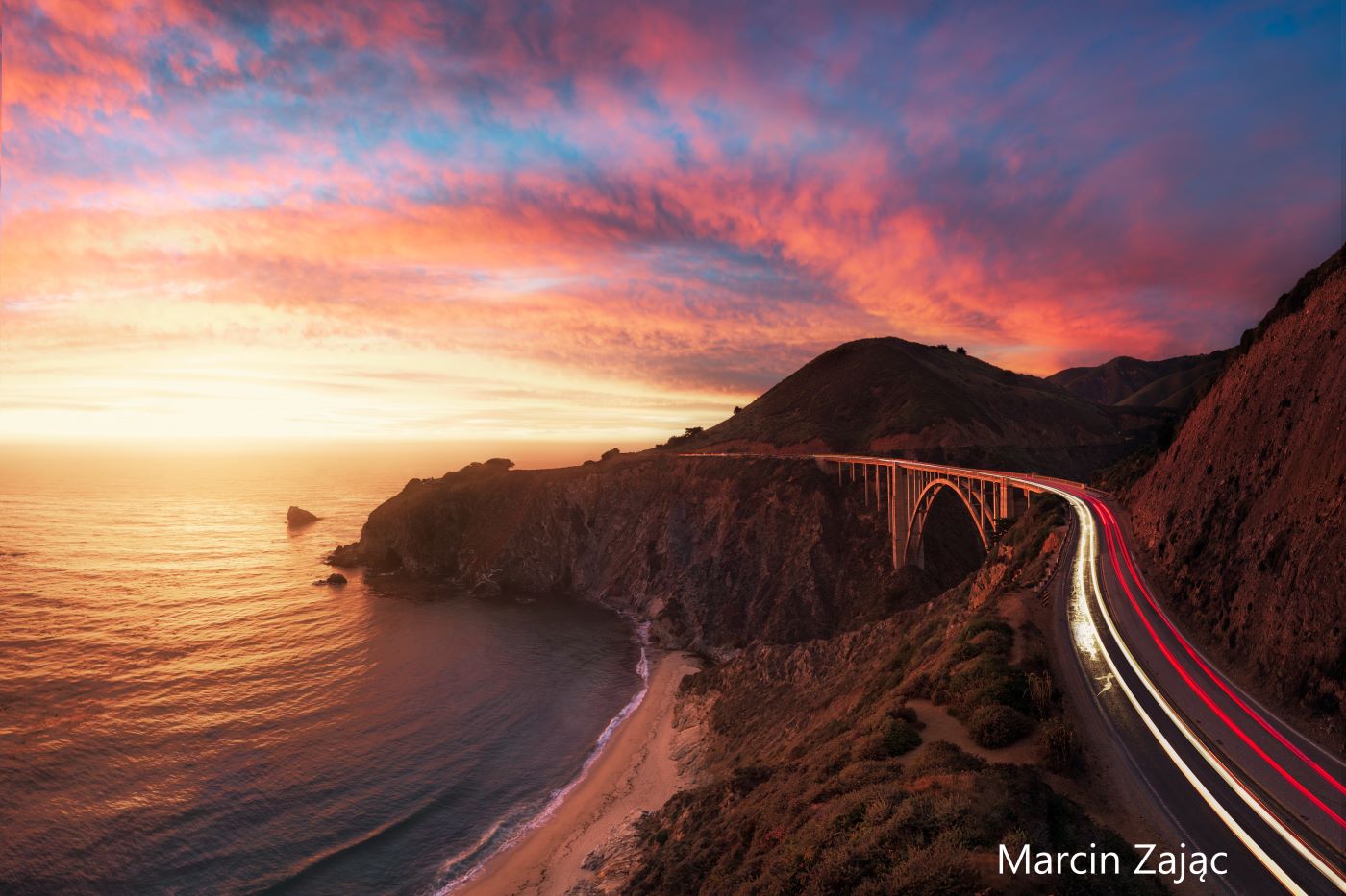 Looking up the shore past sunset as car headlights and breaklights appear as lines of red and white on Highway One south of Bixby Bridge