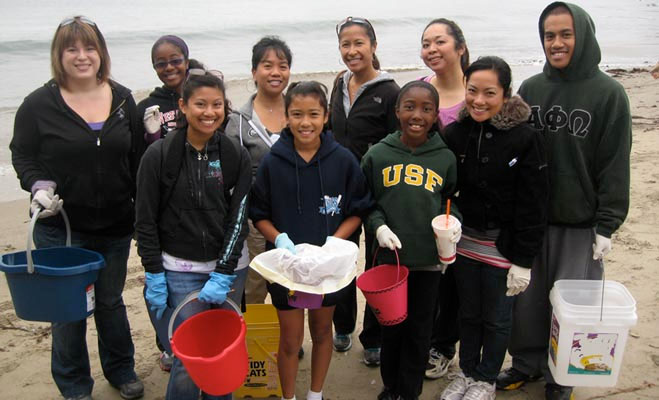 Smiling group of beach cleanup volunteers with buckets