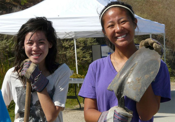 Two young women with shovels and work gloves
