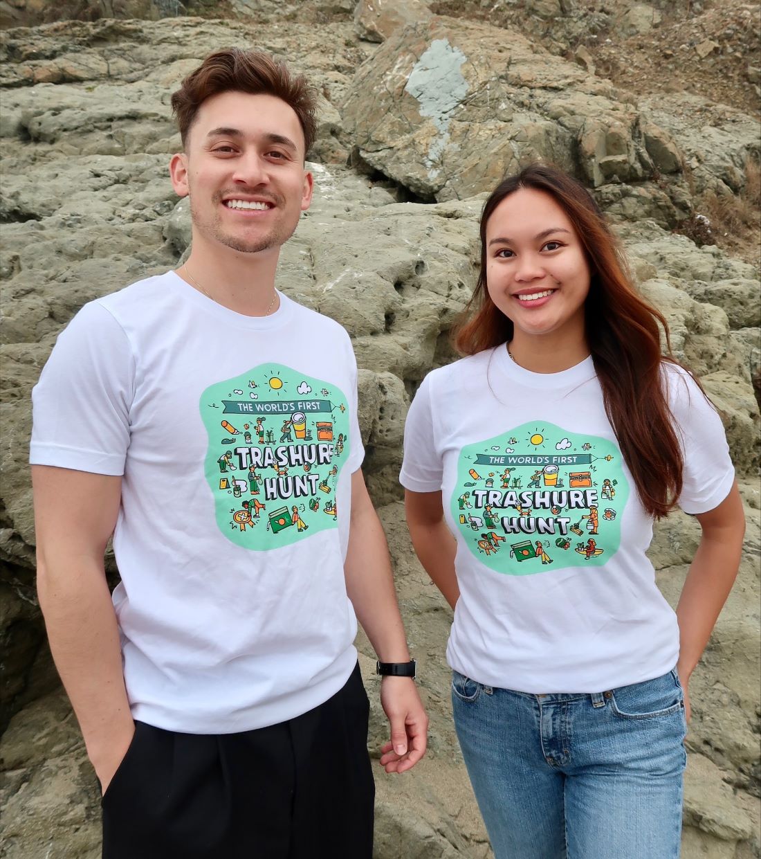 Two people standing in front of beach rocks wearing the 2025 Coastal Cleanup Day shirt